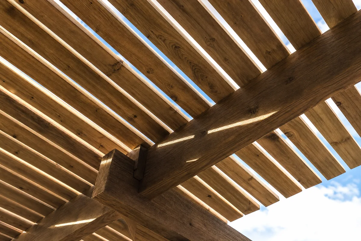 Lames de bois d&rsquo;une pergola vues en contre-plongée sous le soleil